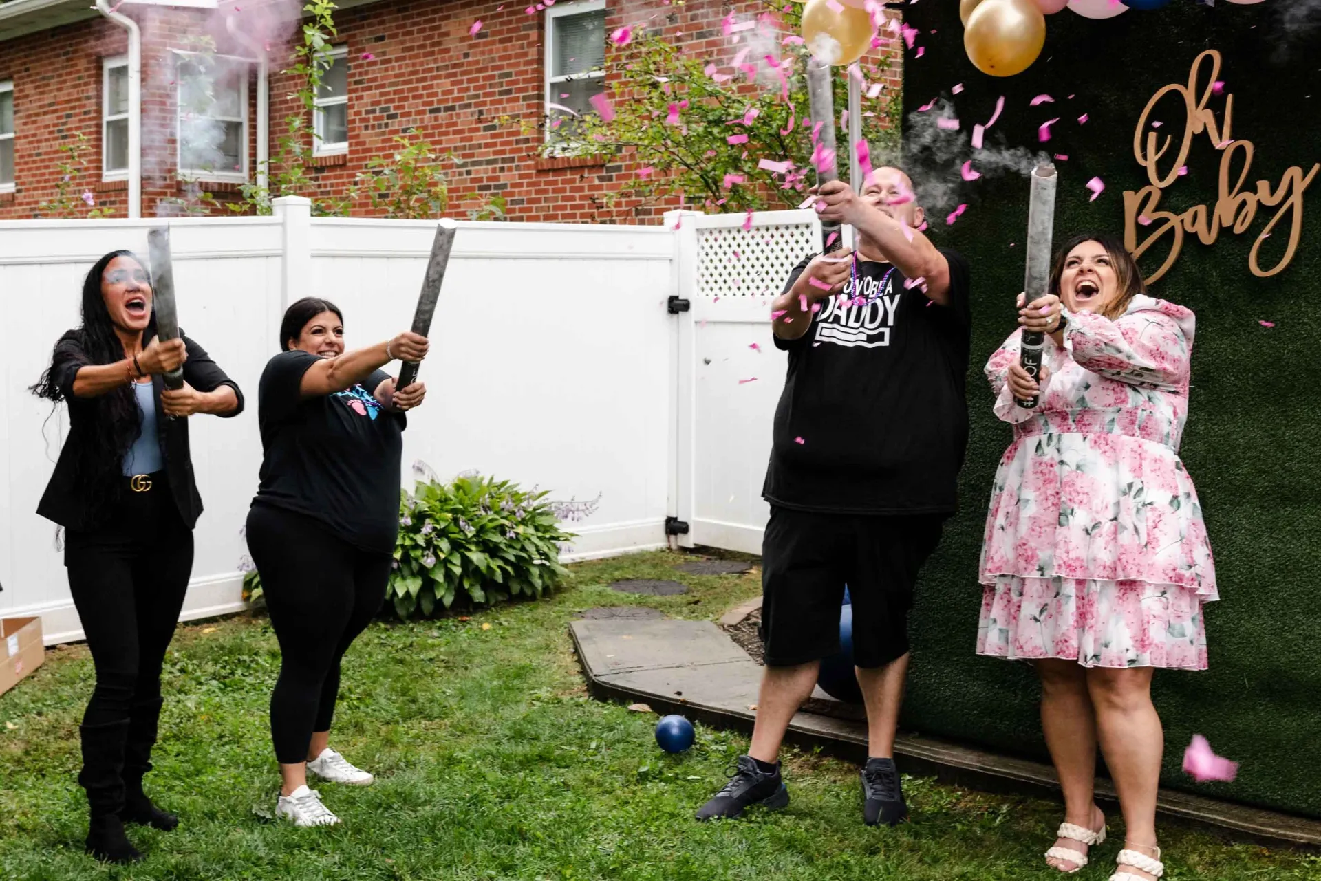 A group of people are standing in the grass holding confetti cannons.