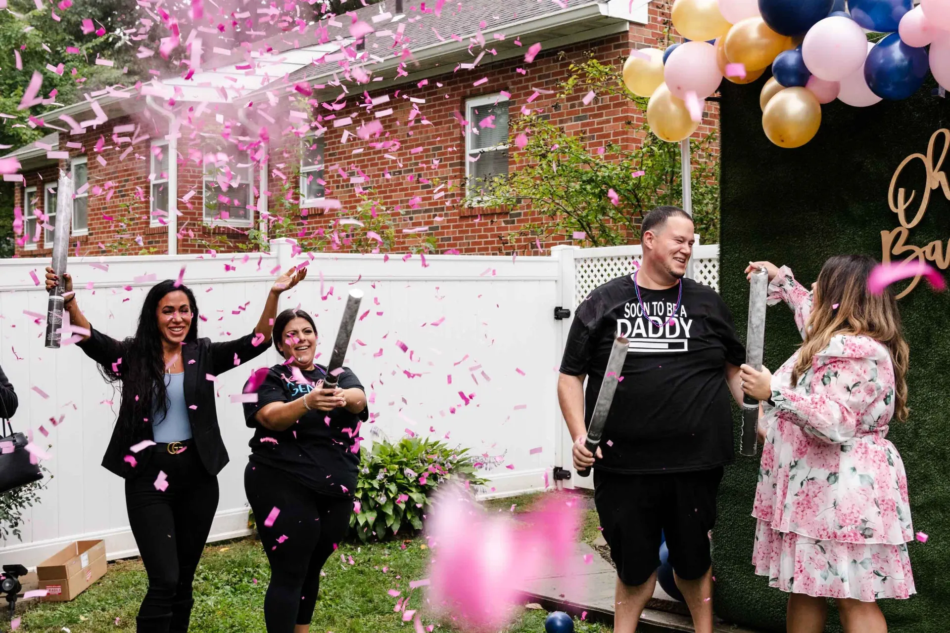 A group of people are throwing confetti and balloons at a gender reveal party.