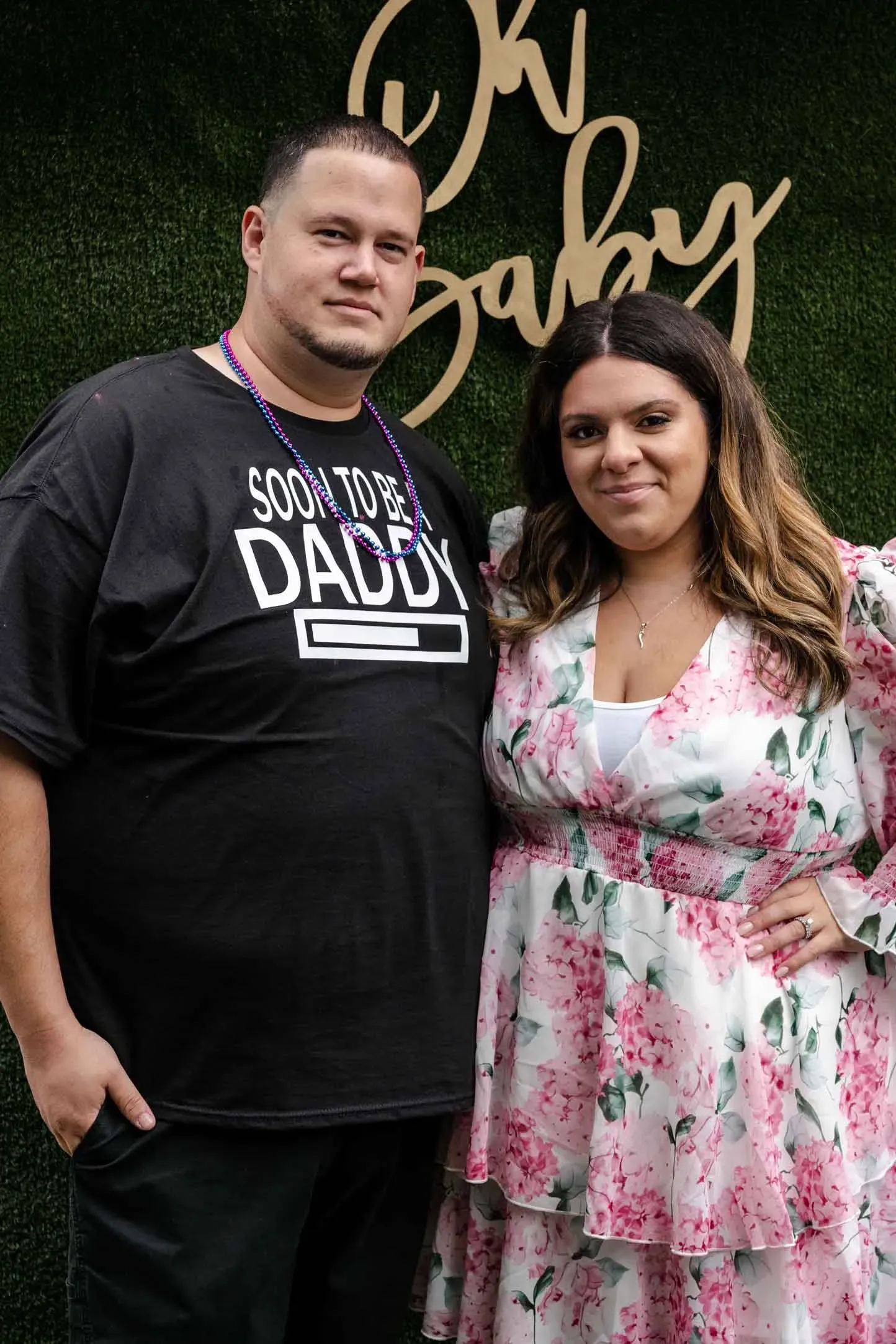 A man and a woman are posing for a picture in front of a wall.