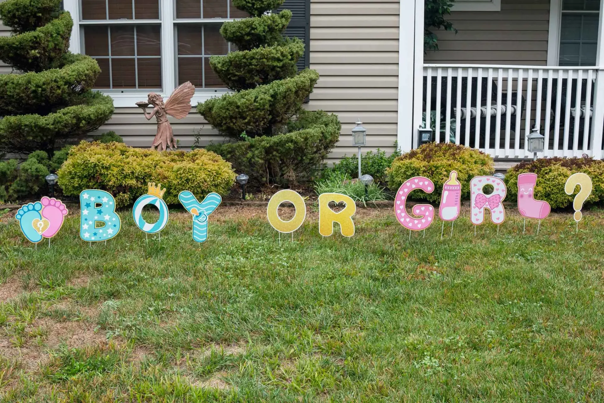 A boy or girl sign is sitting in the grass in front of a house.