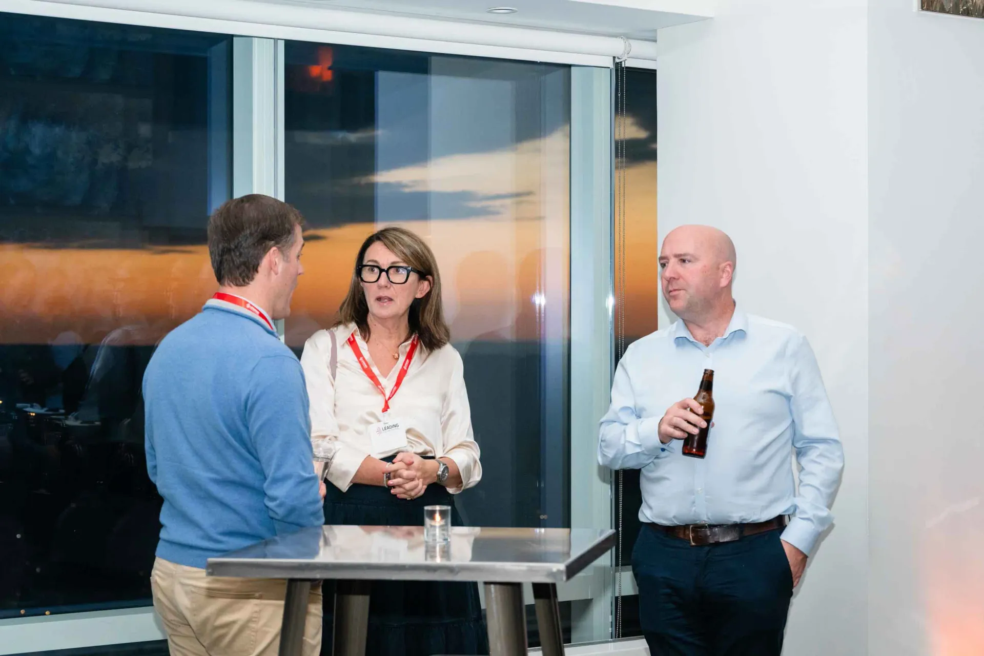 A group of people are standing around a table talking to each other.