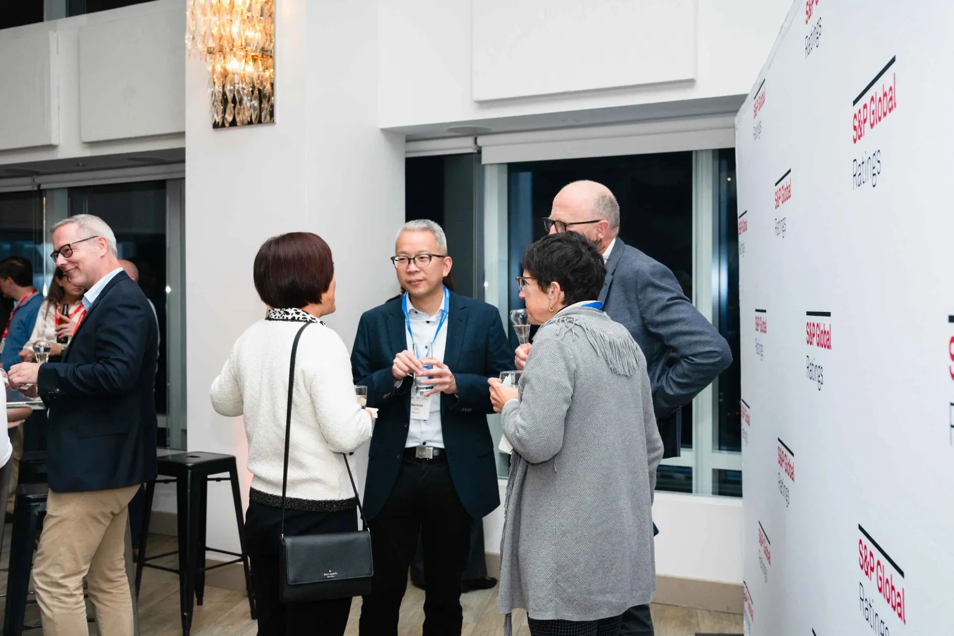 A group of people are standing in a room talking to each other.