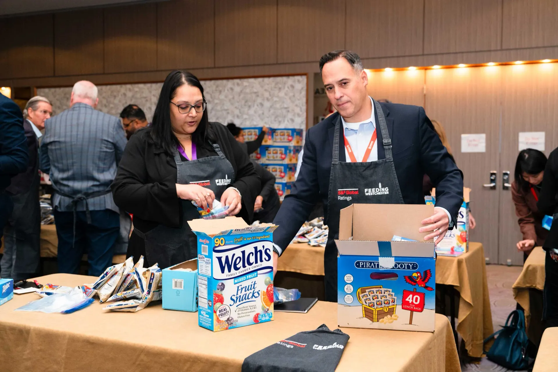 A man and a woman are standing at a table with boxes of welch 's cereal.