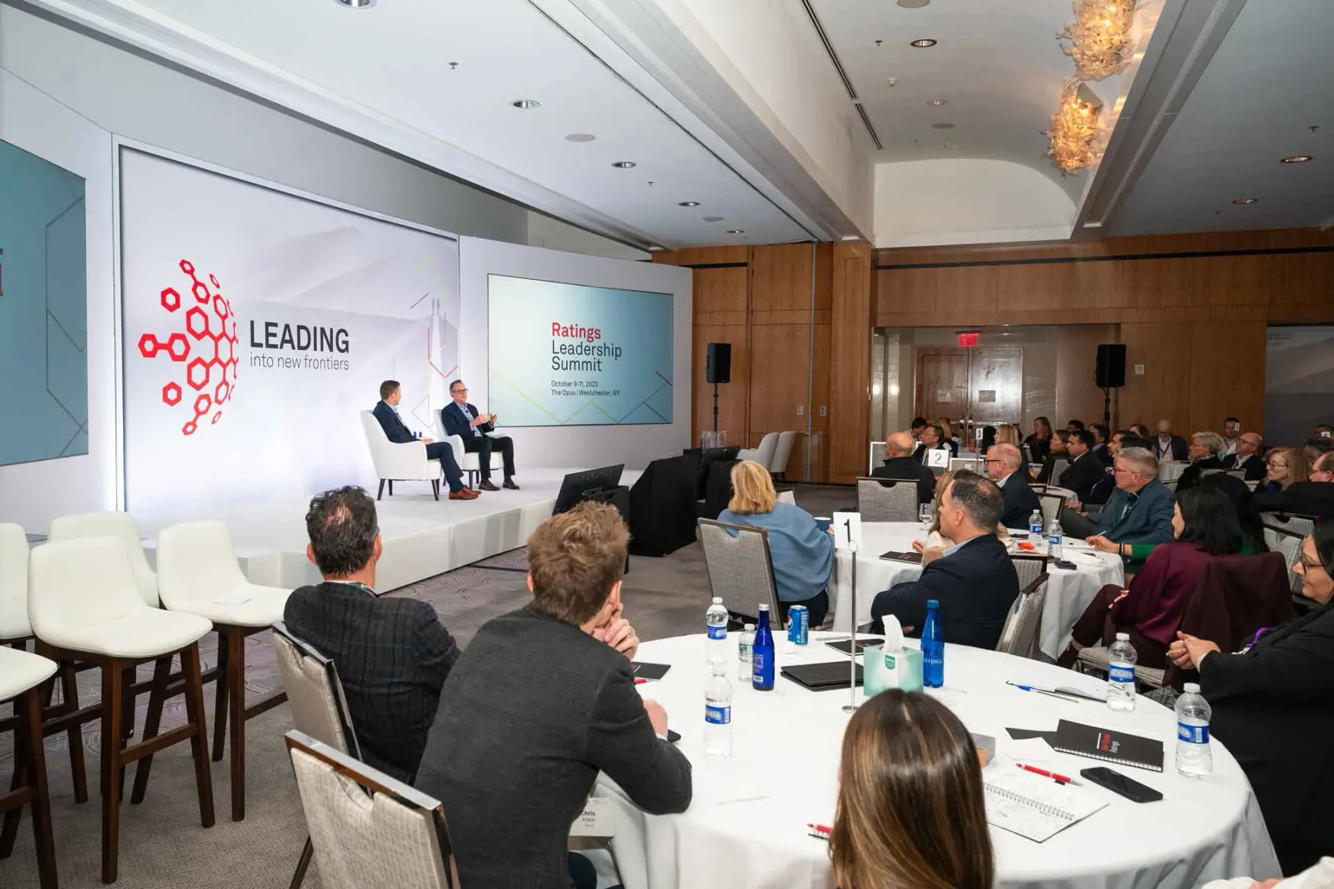 A large group of people are sitting at tables in a conference room.