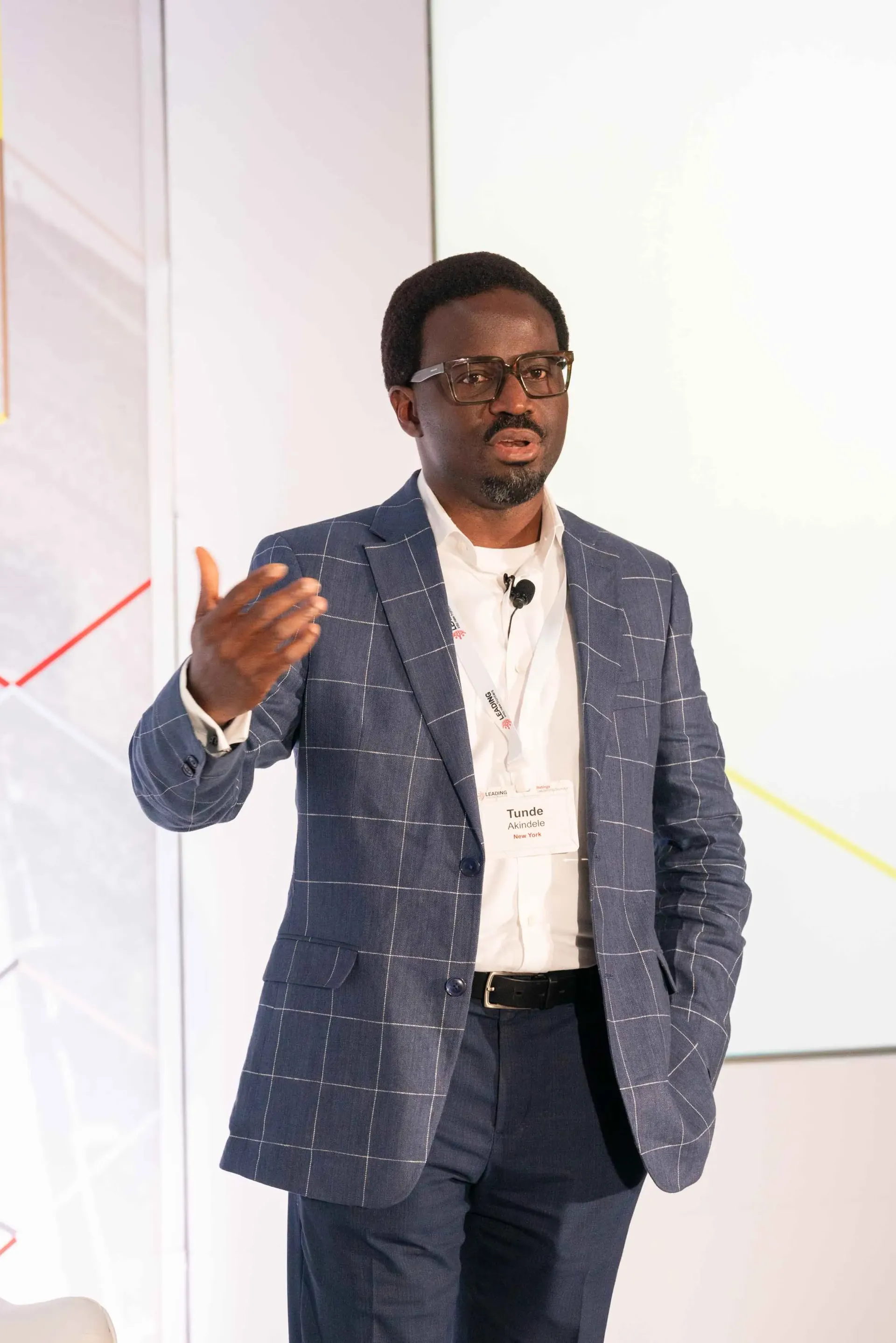 A man in a suit and glasses is giving a presentation.