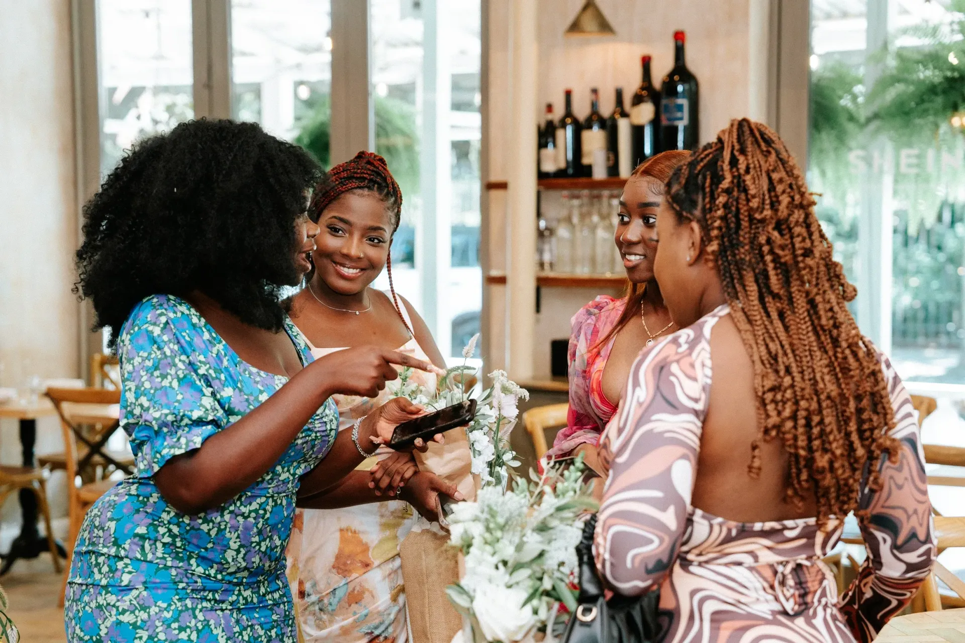 A group of women are standing around a table talking to each other.