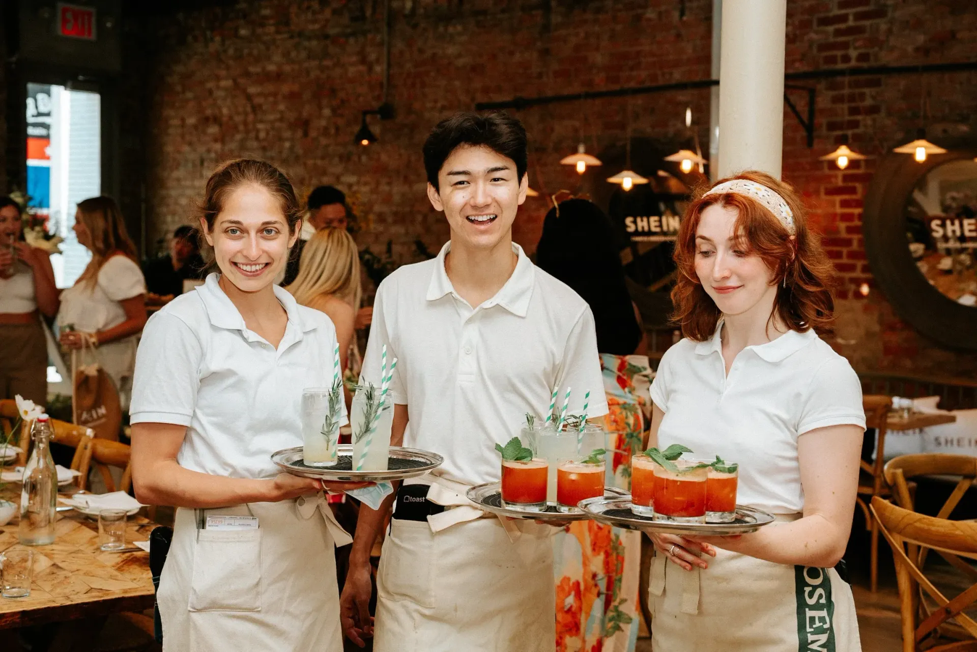 A group of people are standing in a restaurant holding trays of drinks.