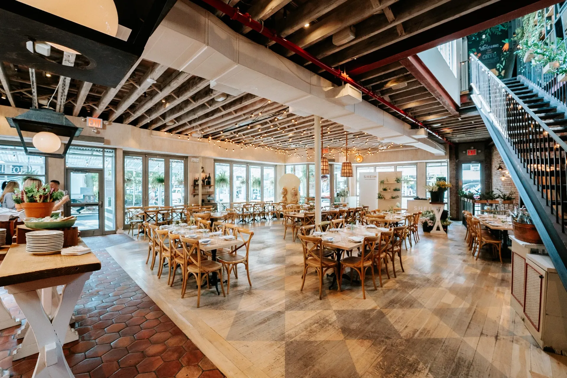 A large restaurant with tables and chairs and a staircase.
