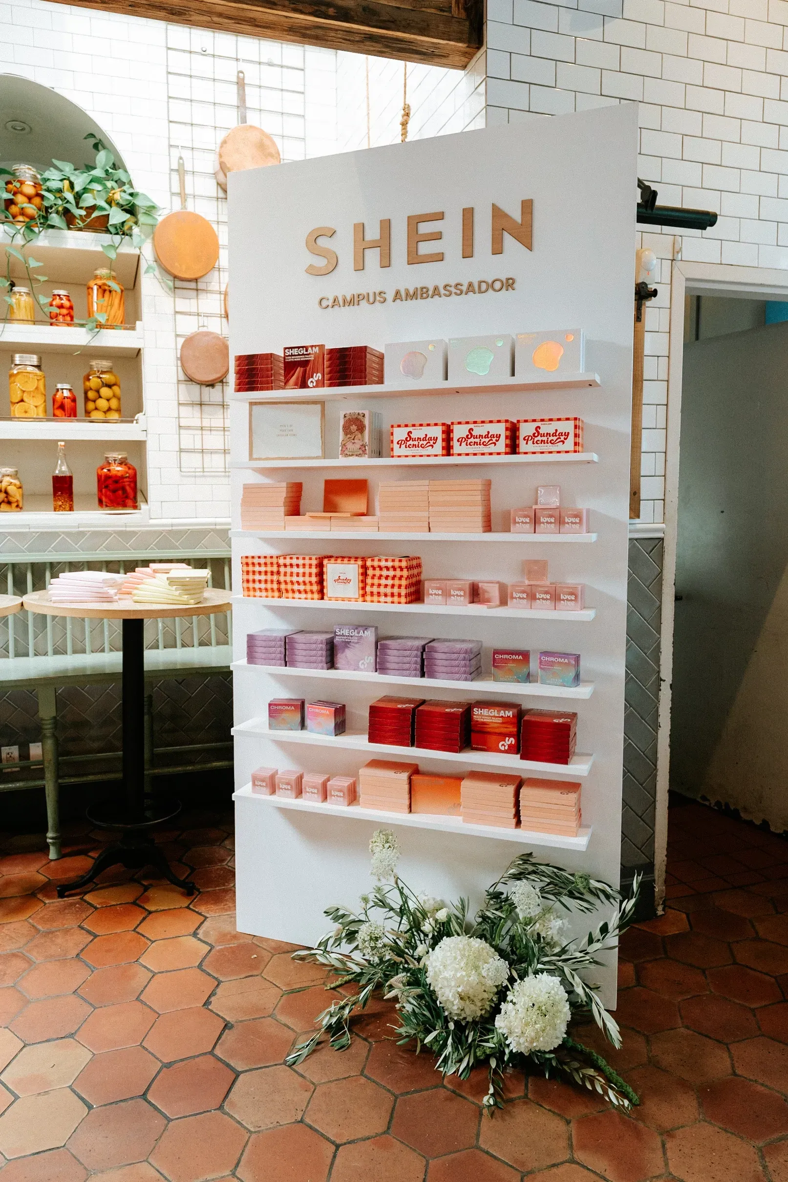 A shein display with flowers in front of it in a store.