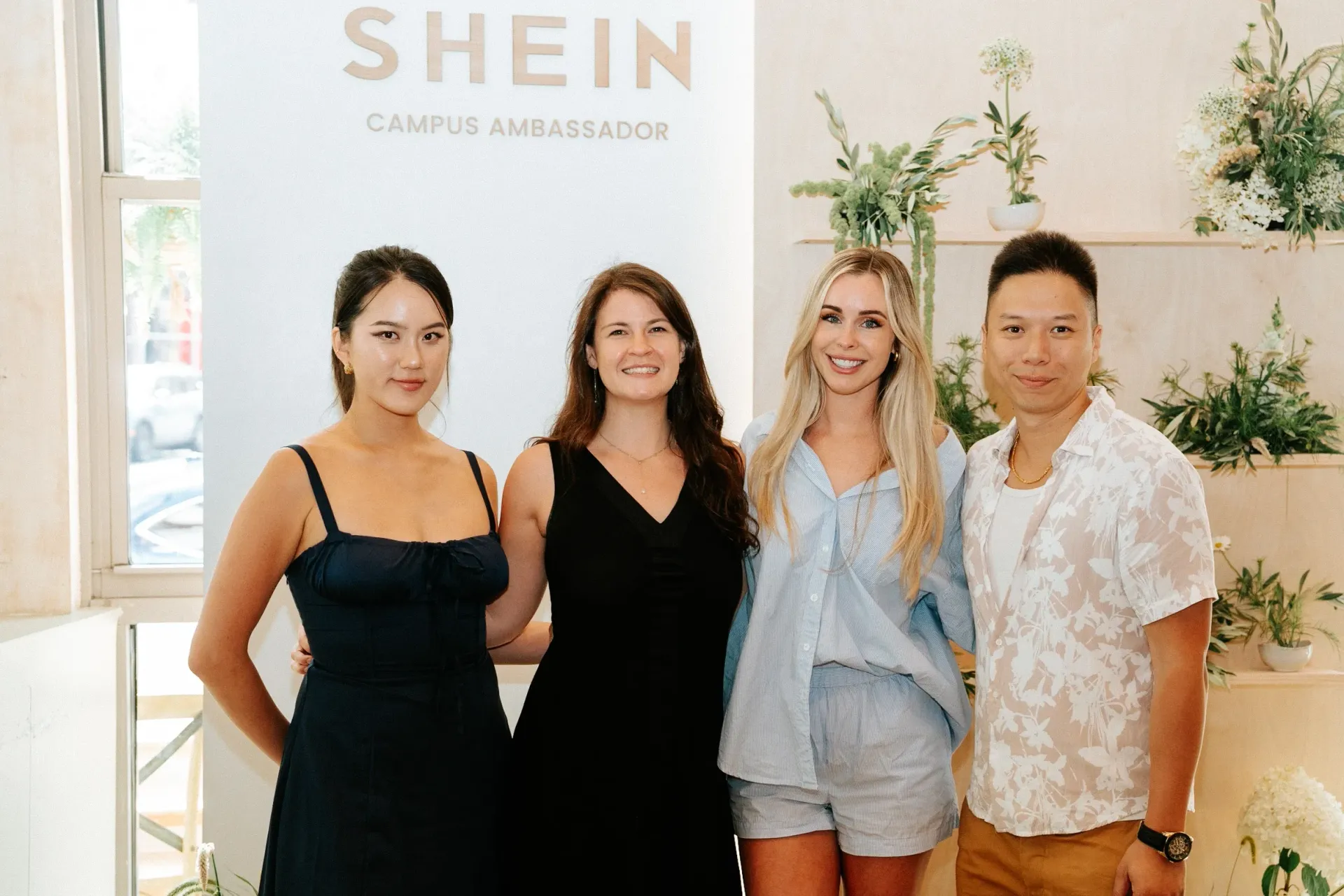 A group of people are posing for a picture in front of a shein sign.