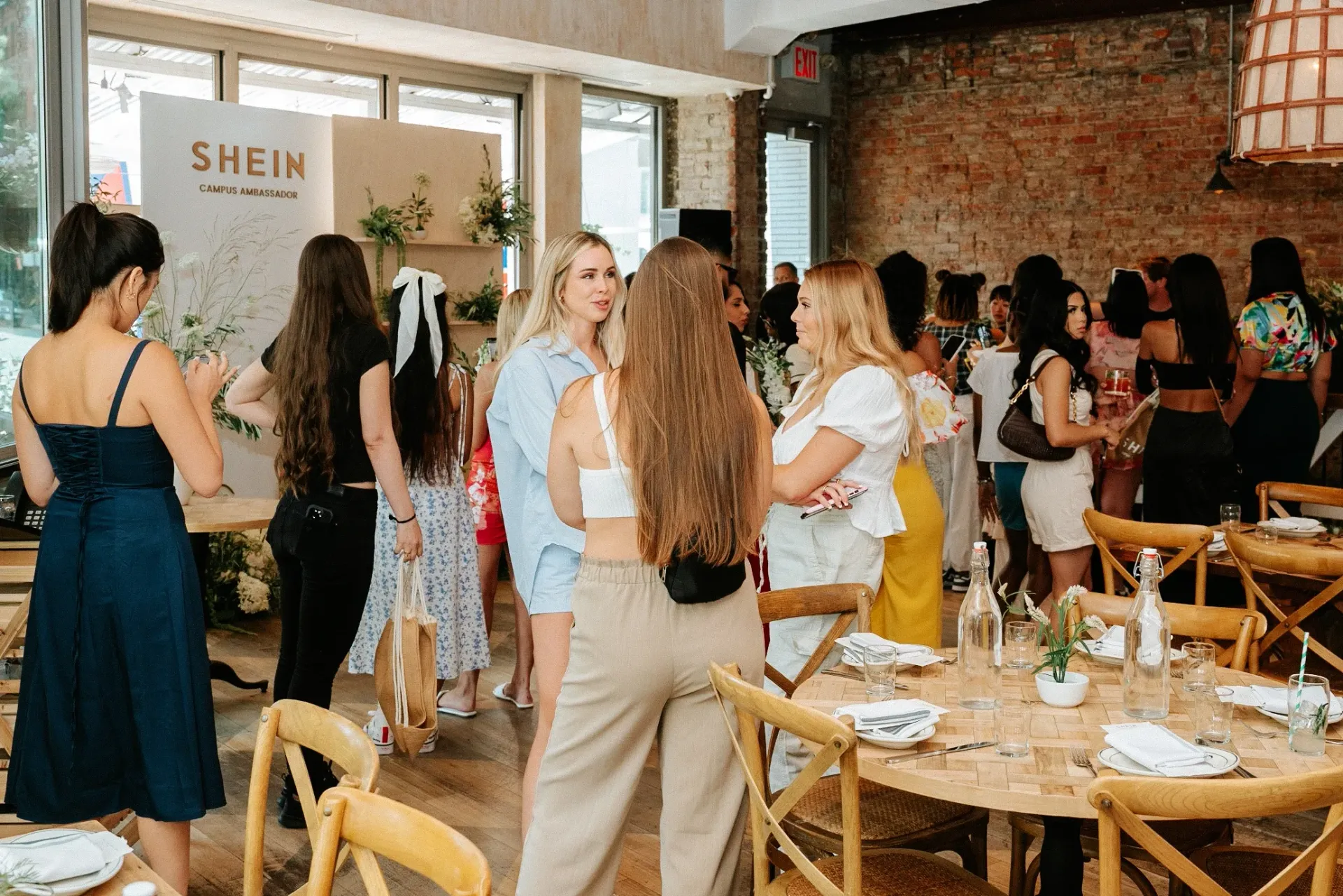 A group of women are standing around tables in a restaurant.