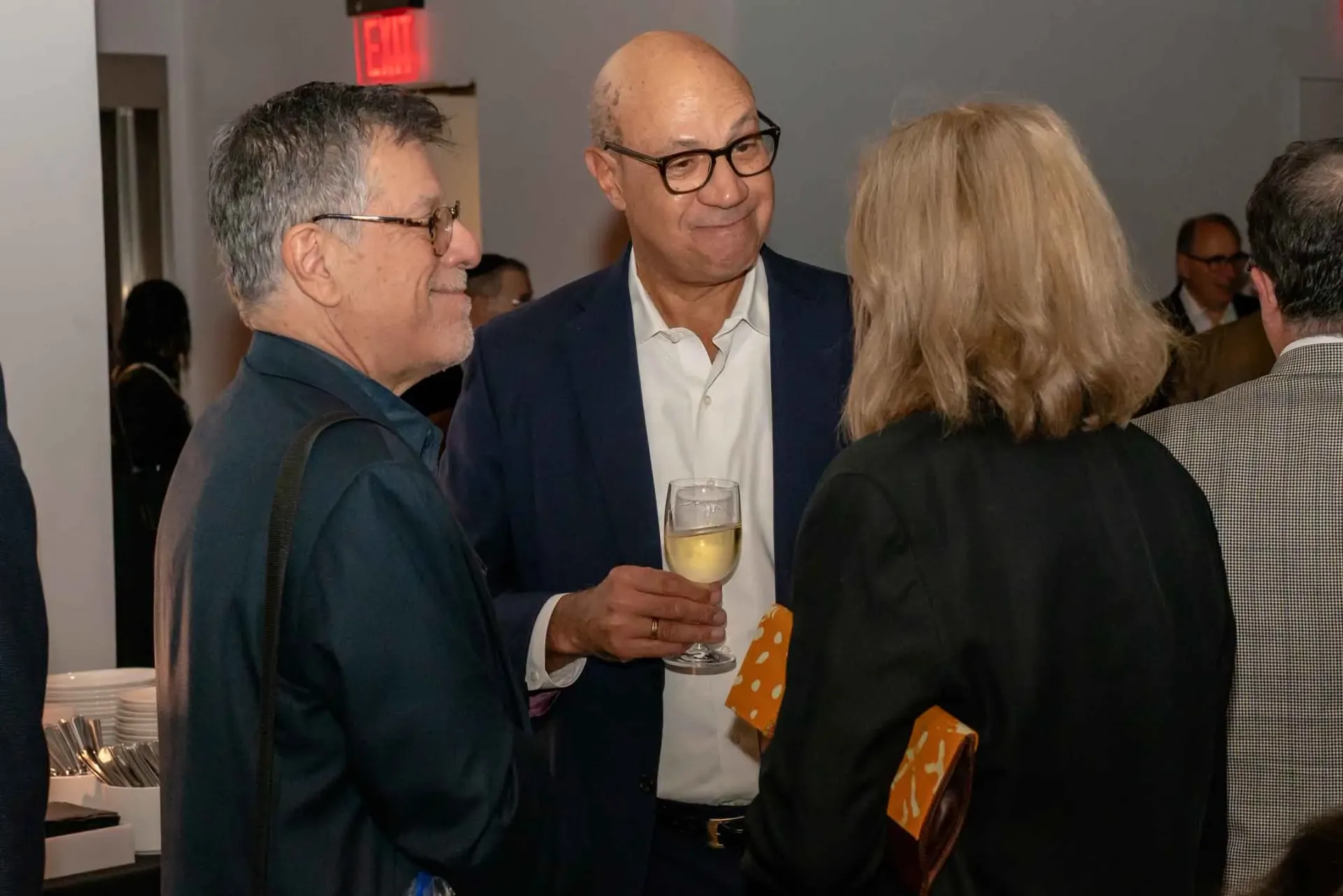 A group of people are standing in a room talking to each other.