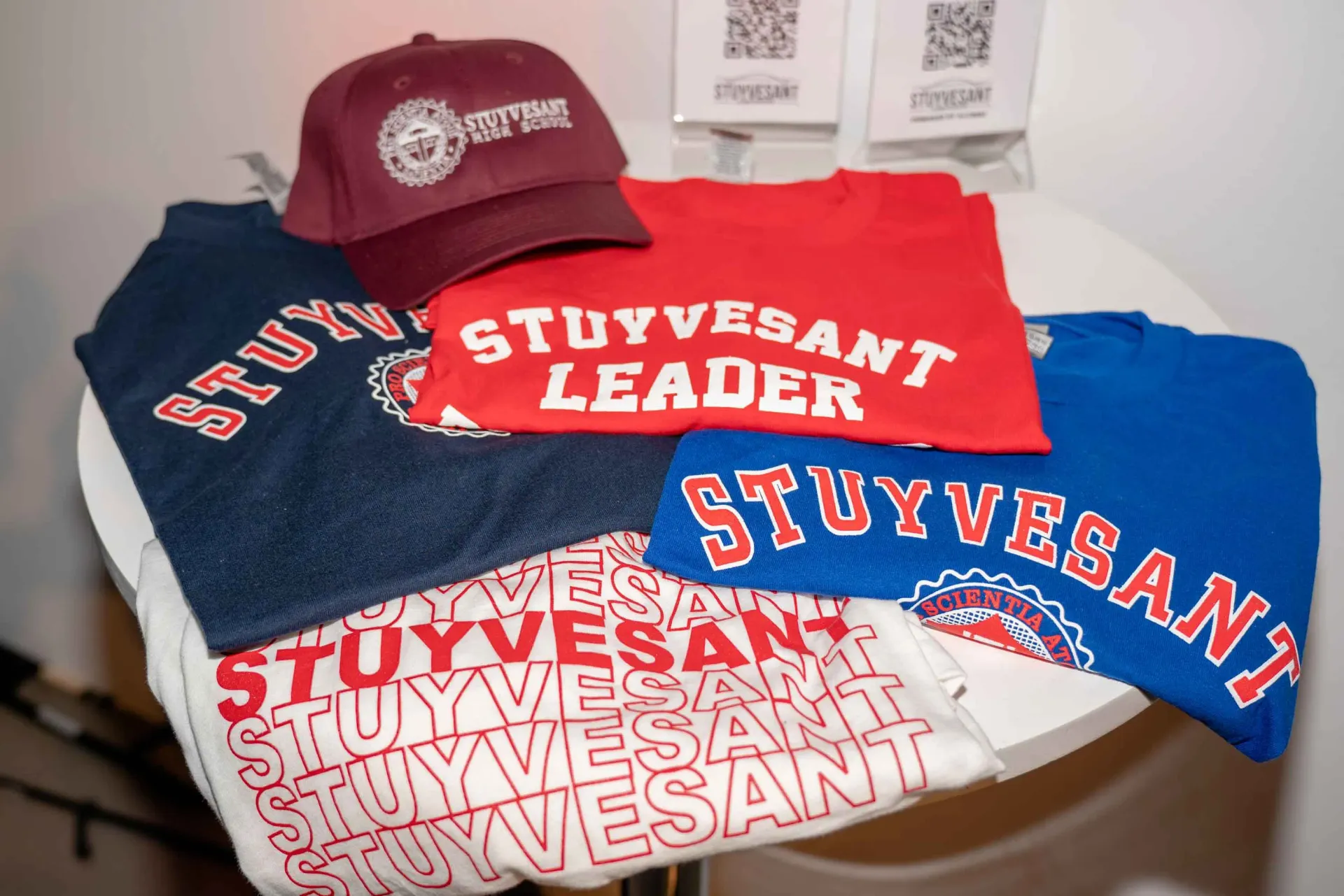 A bunch of stuyvesant shirts and hats on a table