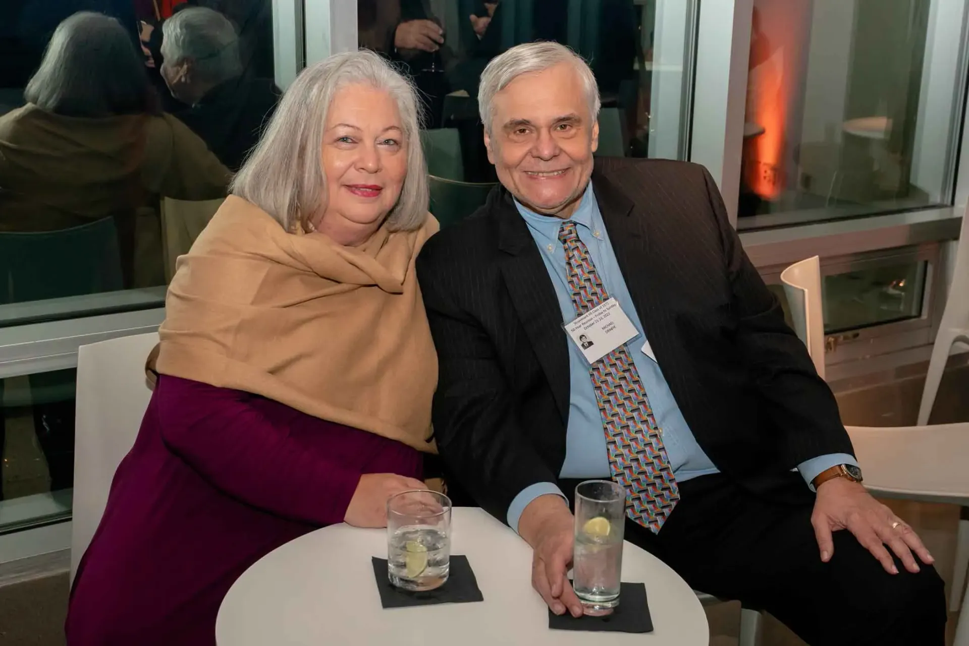 A man and a woman are sitting at a table with drinks.