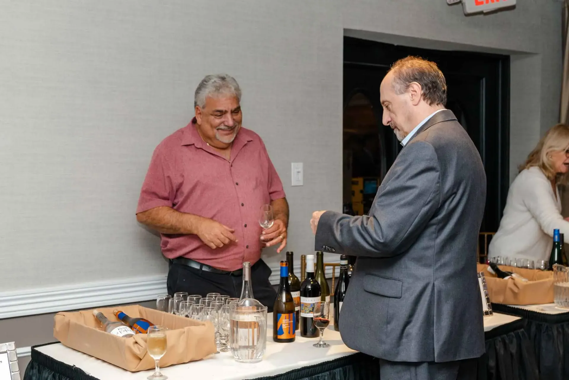 Two men are standing at a table talking to each other.