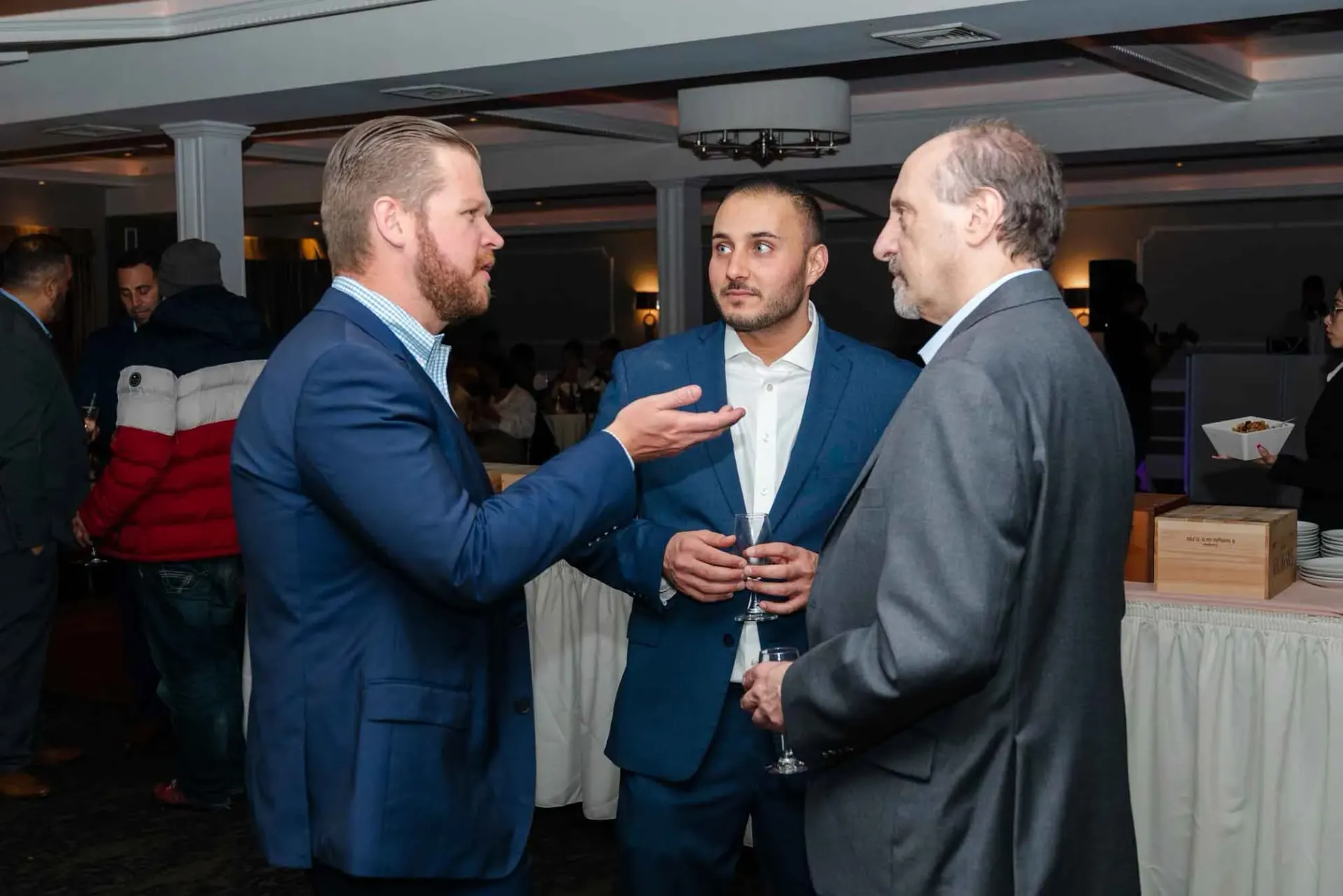 Three men in suits are talking to each other in a room.