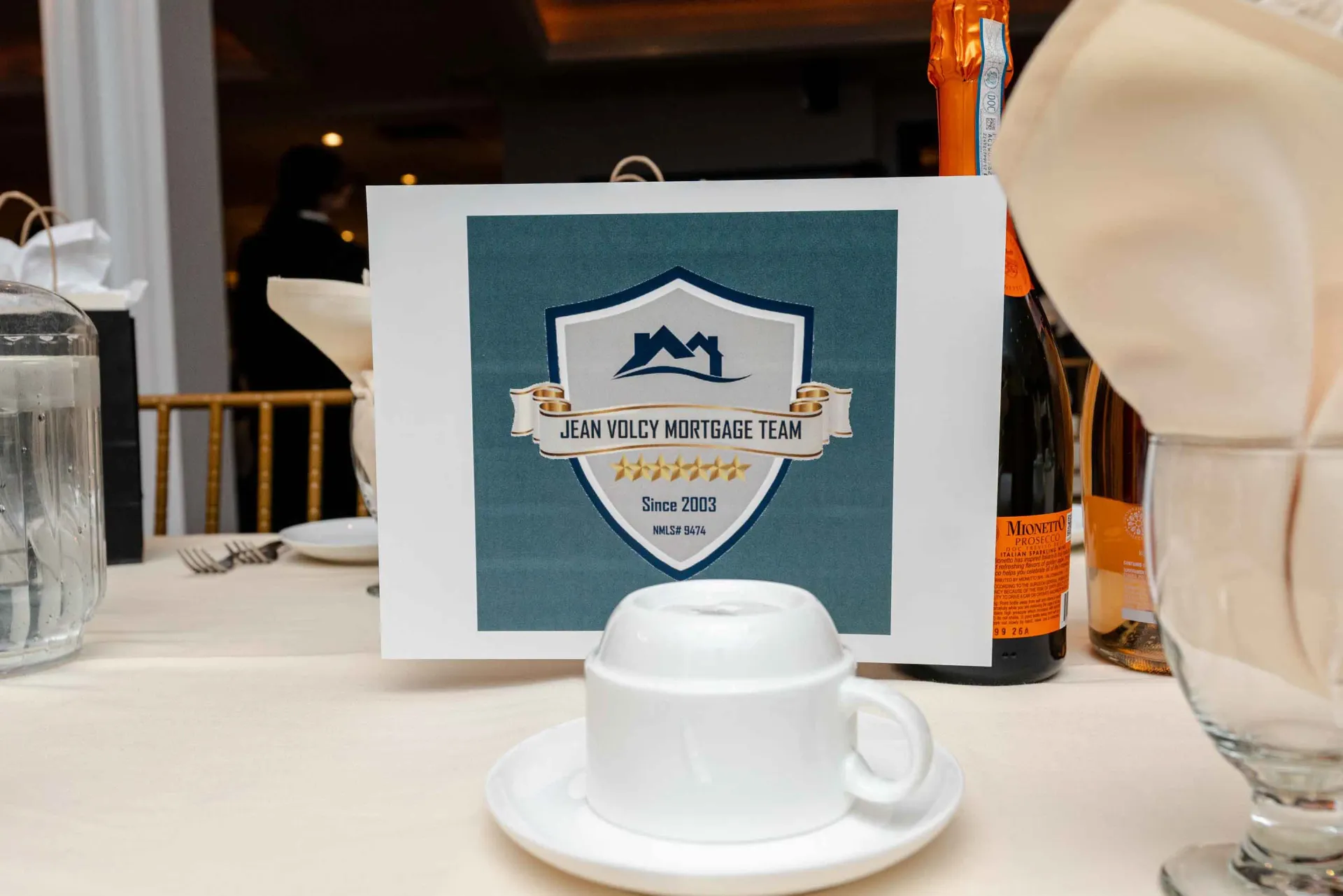 A table with a cup and saucer and a sign on it