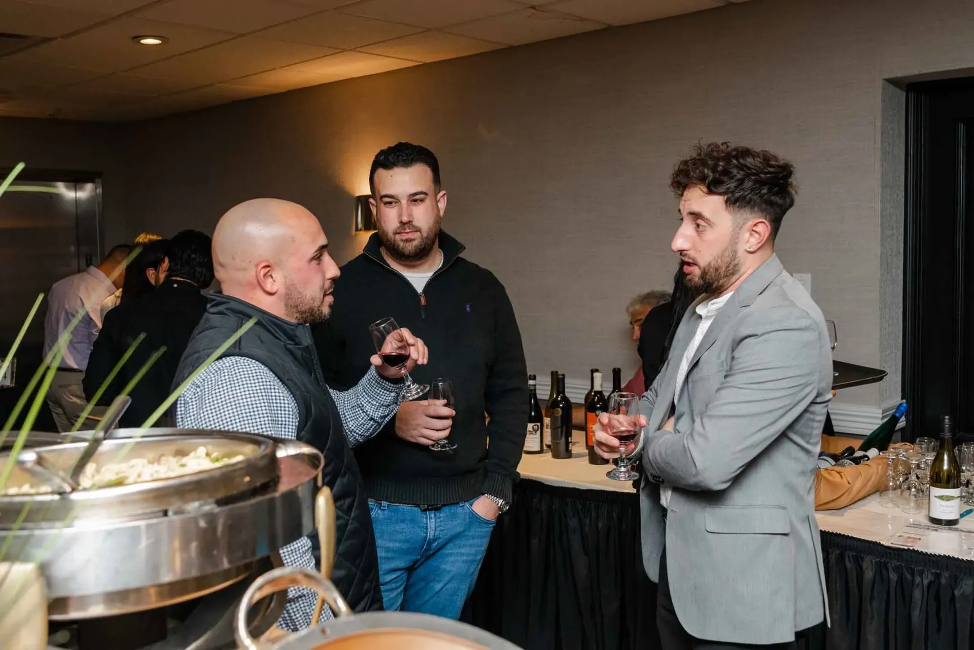 A group of men are standing in a room talking to each other.