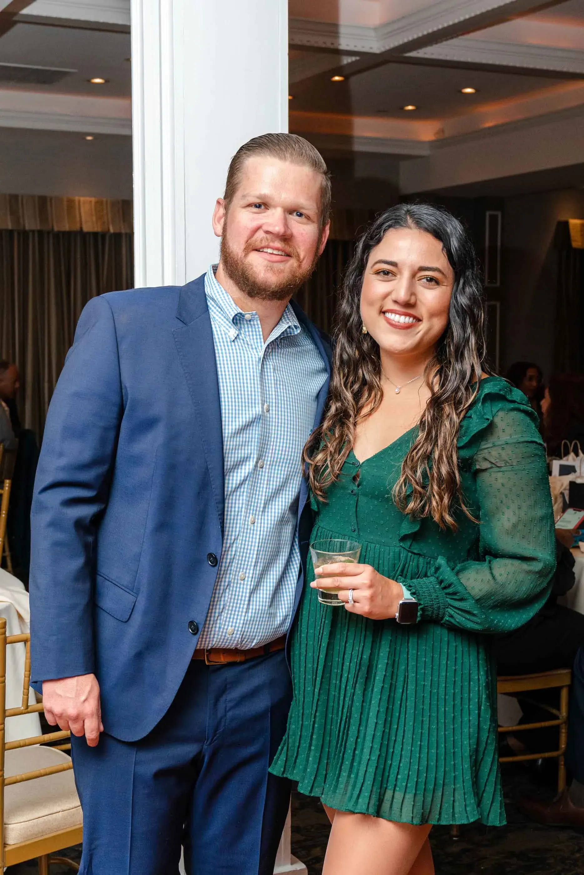 A man in a suit and a woman in a green dress are posing for a picture.