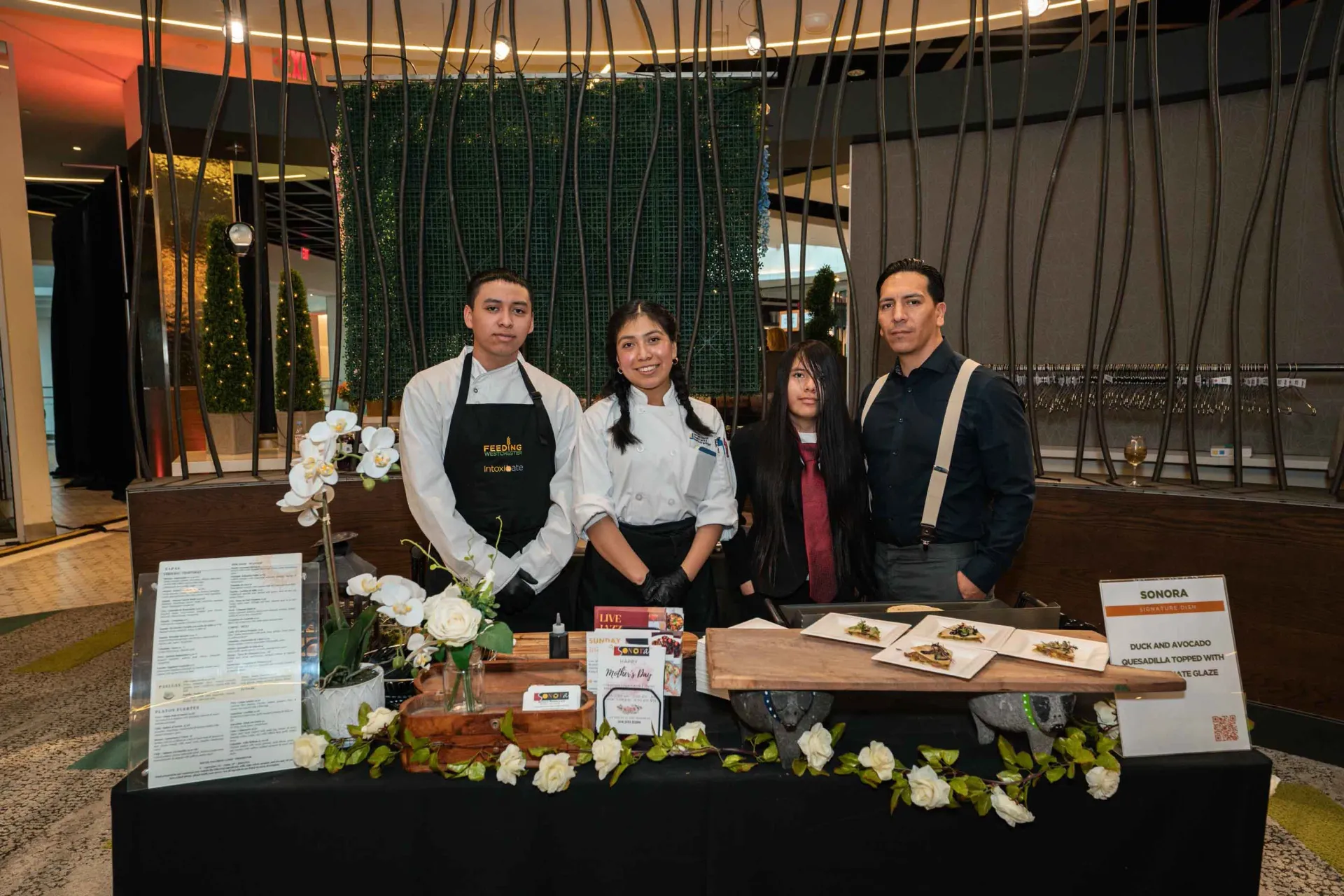 A group of people are standing around a table.