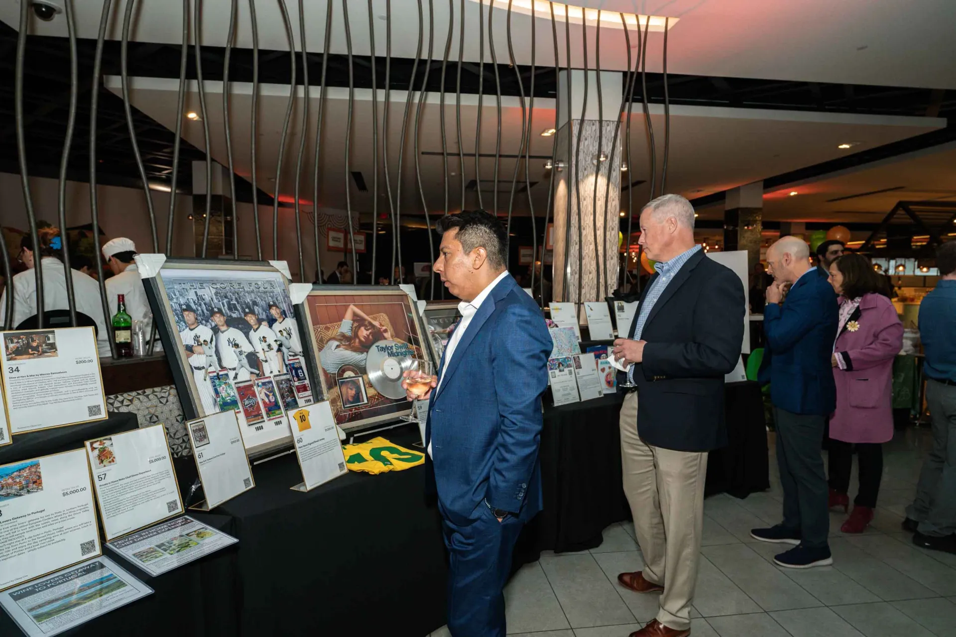 A group of people are standing around a table looking at paintings.
