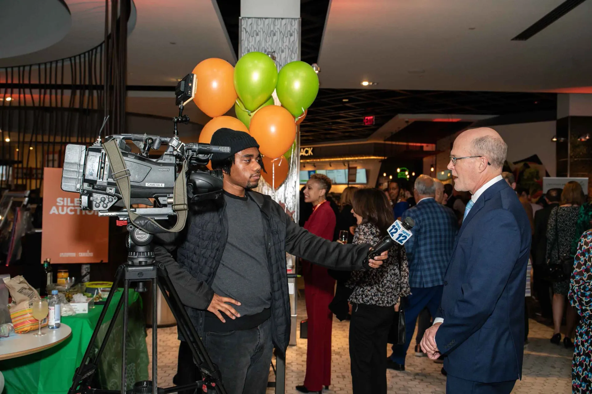 A man is standing in front of a camera talking to a group of people.