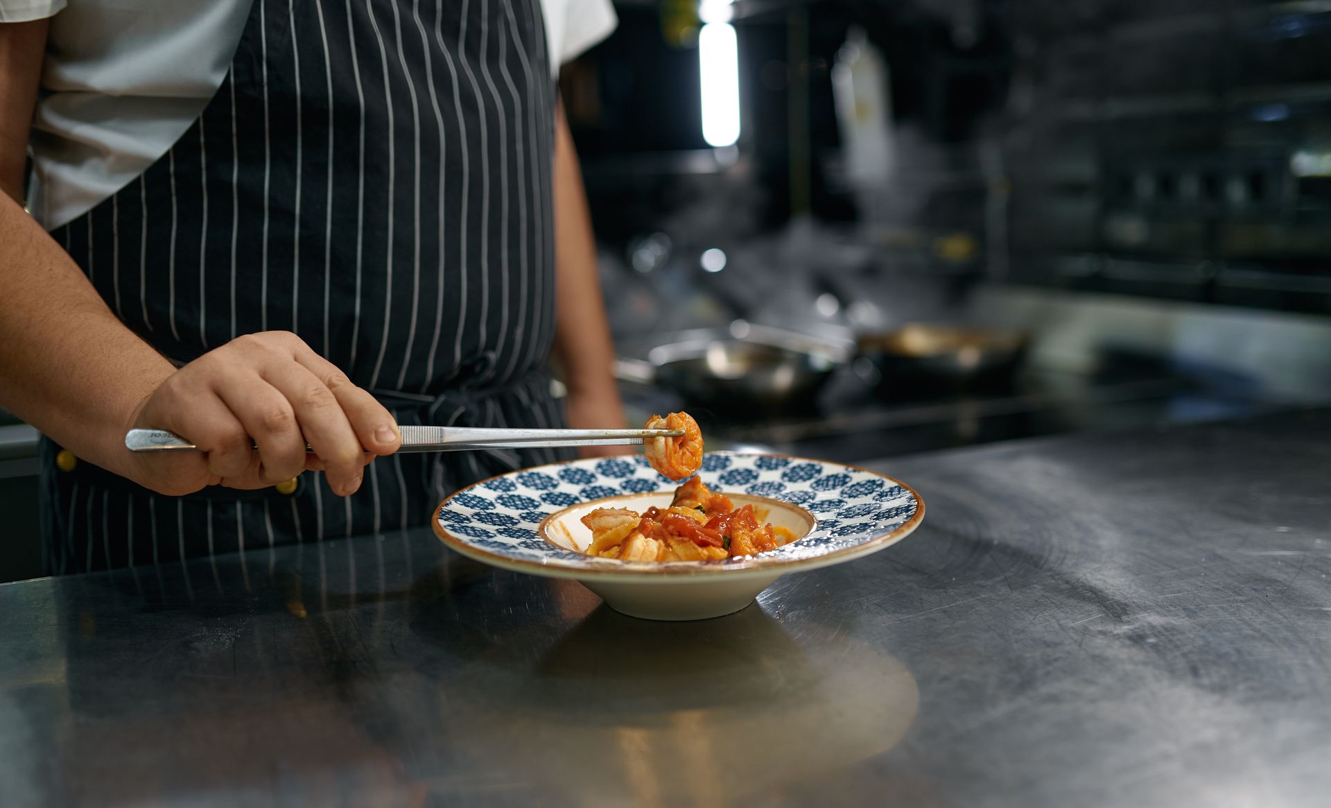 A chef is preparing a plate of food in a kitchen.