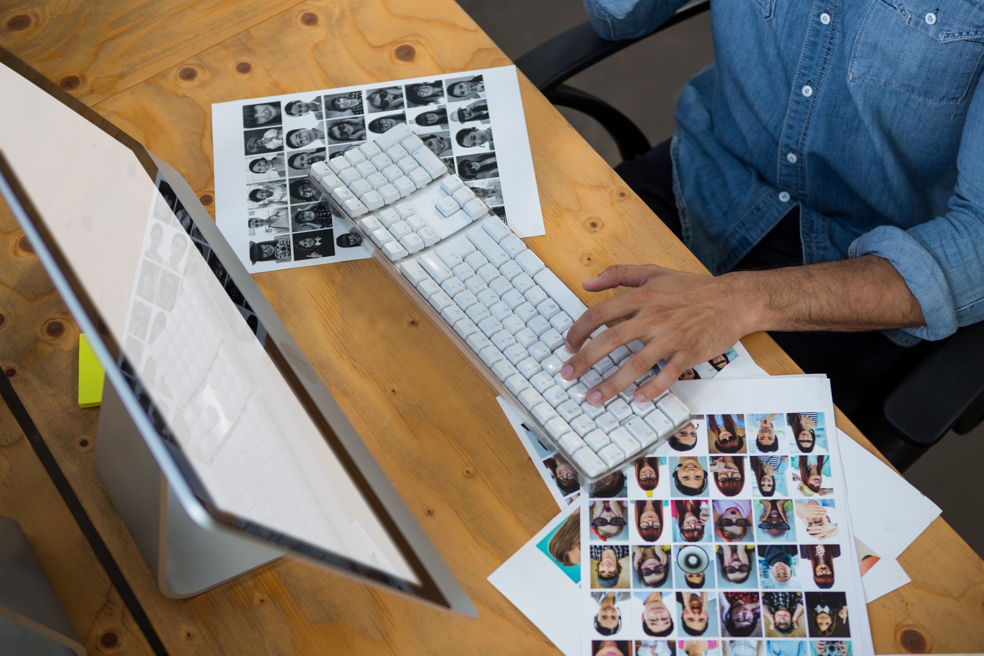 A man is sitting at a desk typing on a computer keyboard.