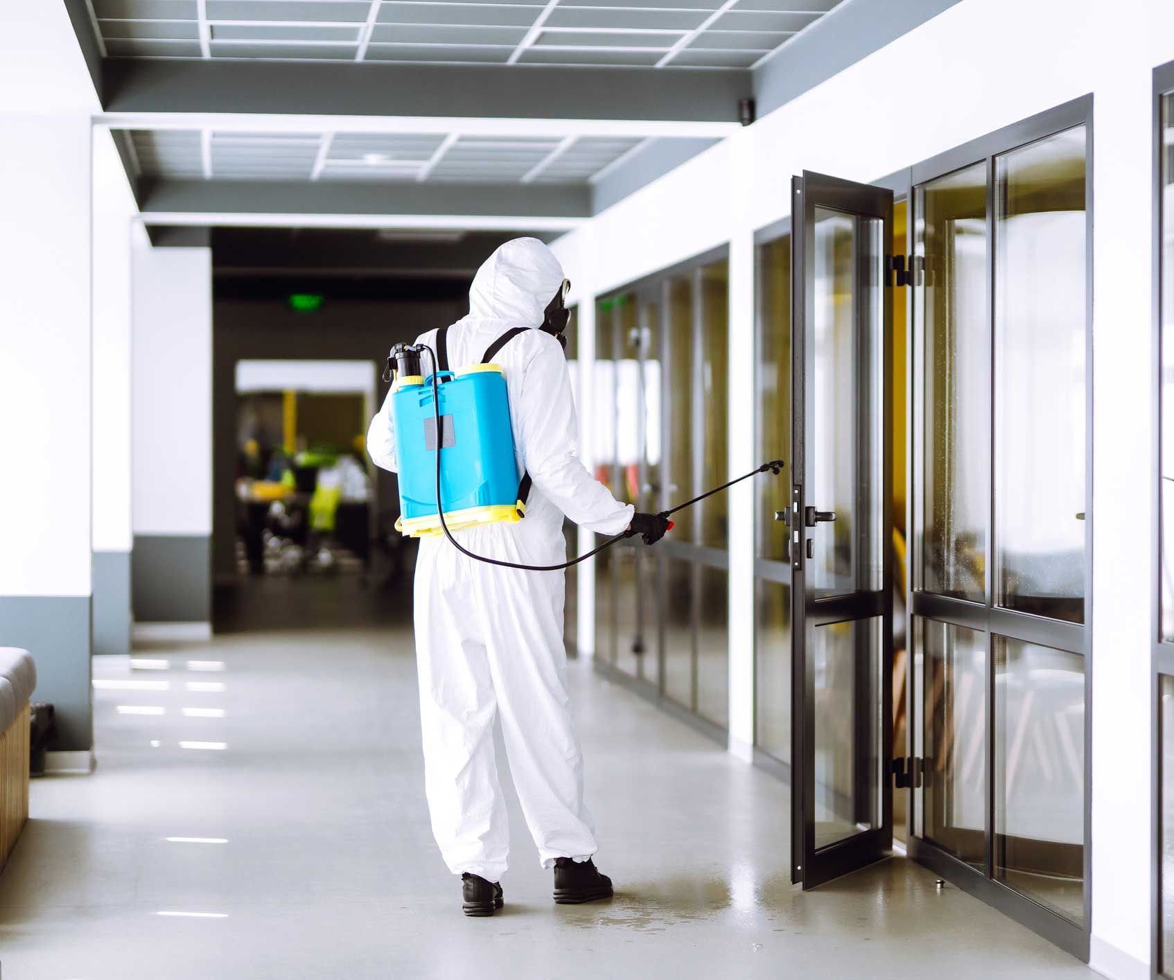 A man in a protective suit is disinfecting a building.