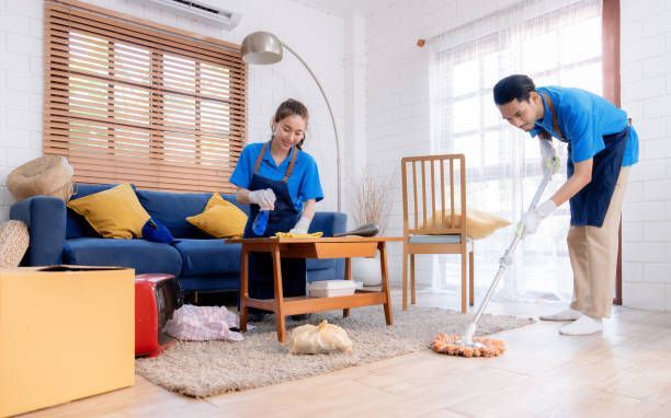 A man and a woman are cleaning a living room.