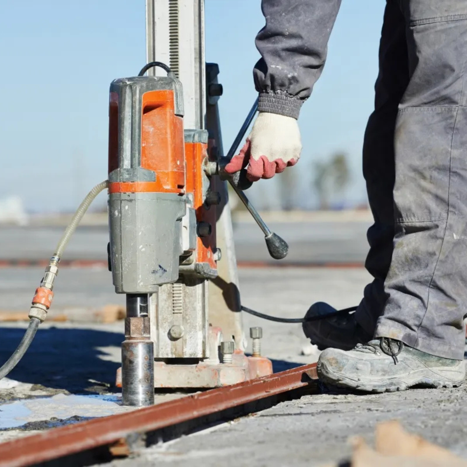 Person using an angle grinder to cut a concrete paving stone, creating dust.