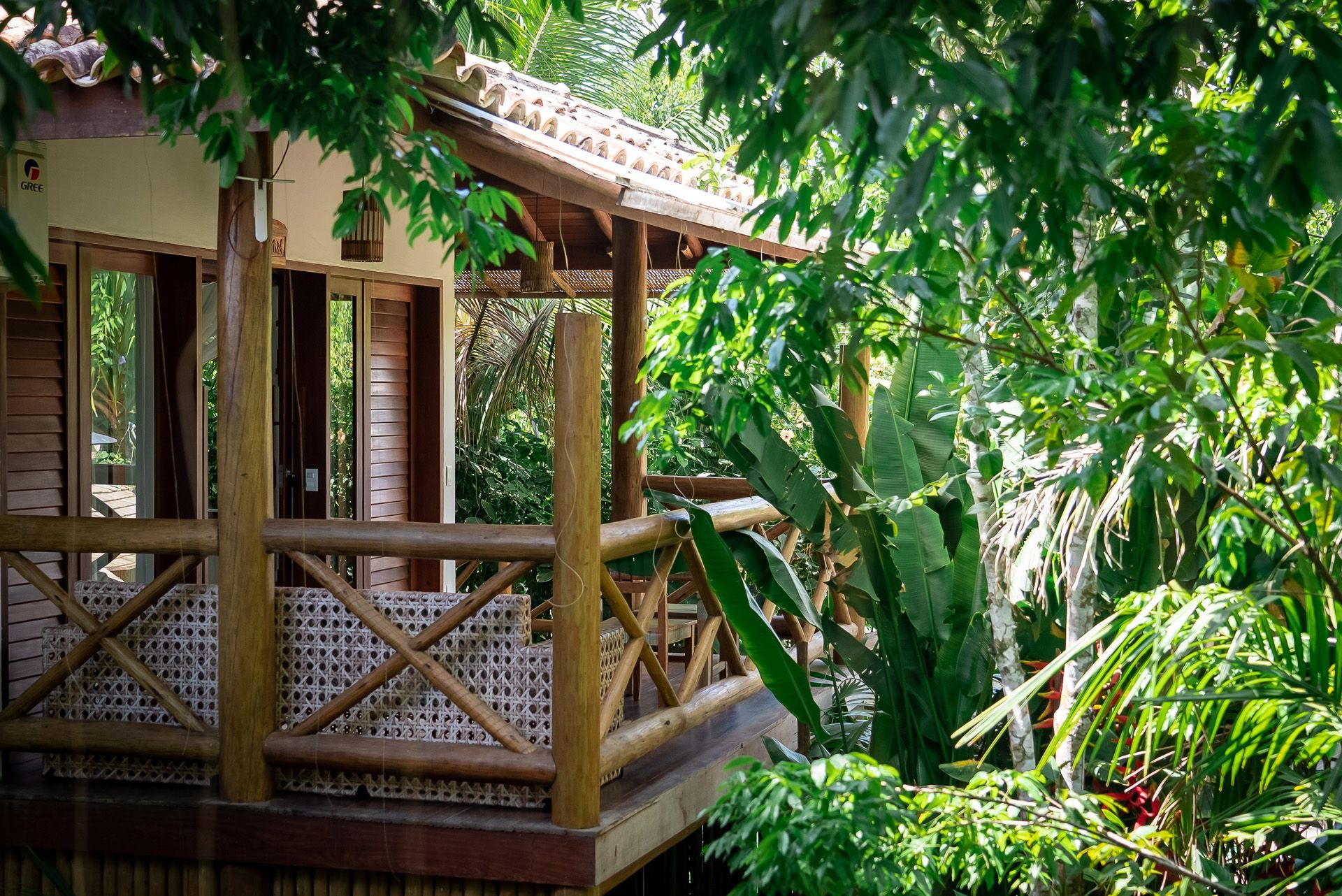 Cabana de madeira com varanda rodeada por folhagem verdejante.