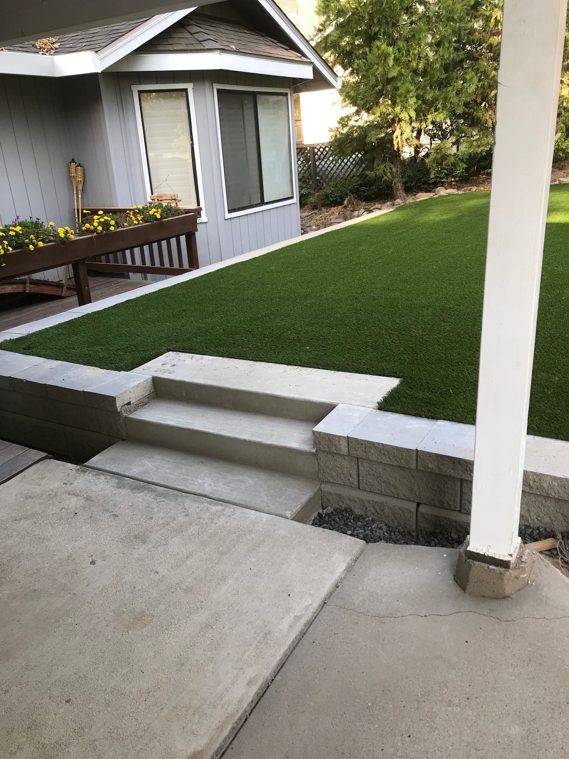 A house with a lush green lawn and stairs leading up to it.