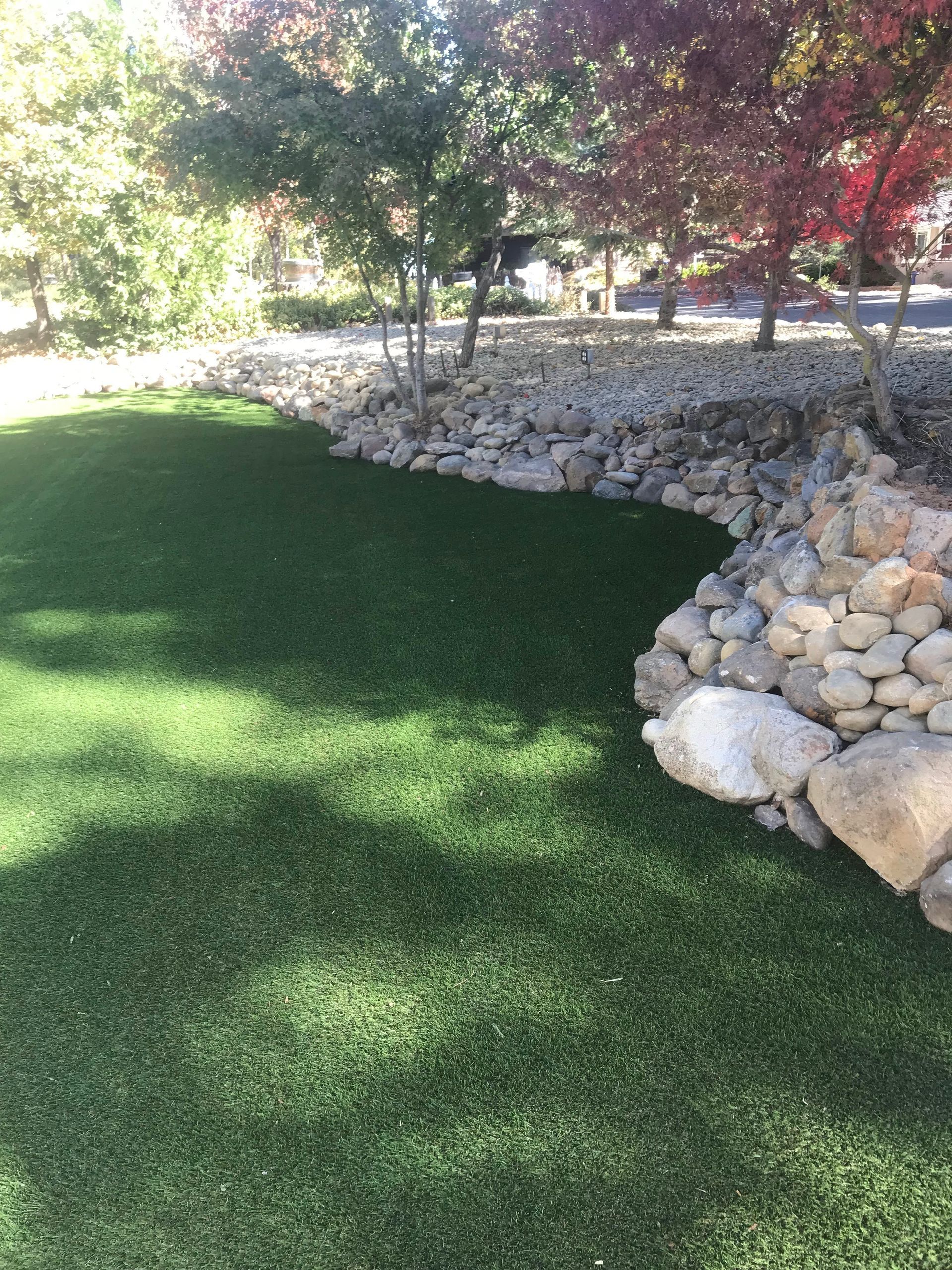 A lush green lawn with rocks and trees in the background.