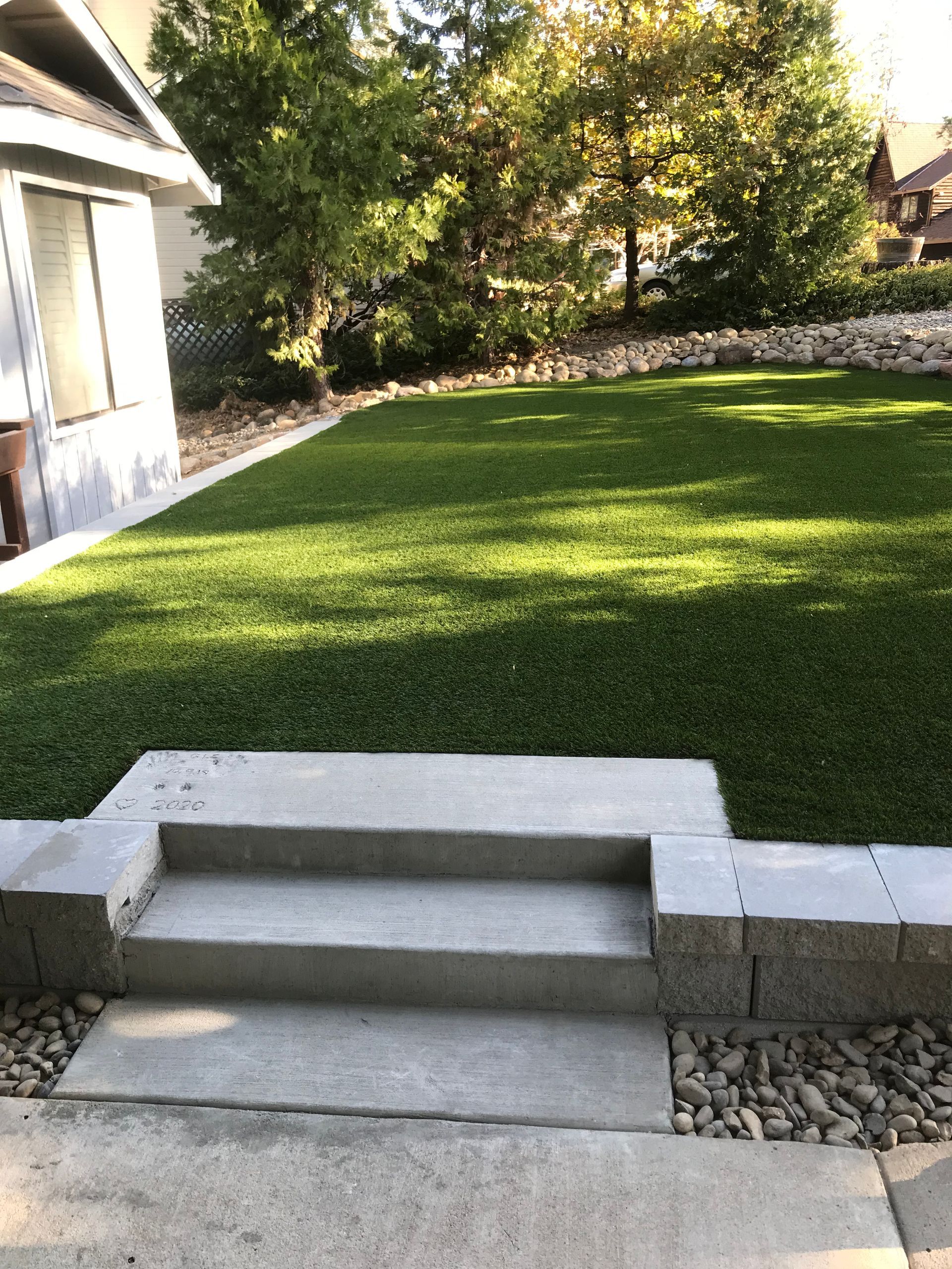 A lawn with stairs leading up to it and a house in the background.
