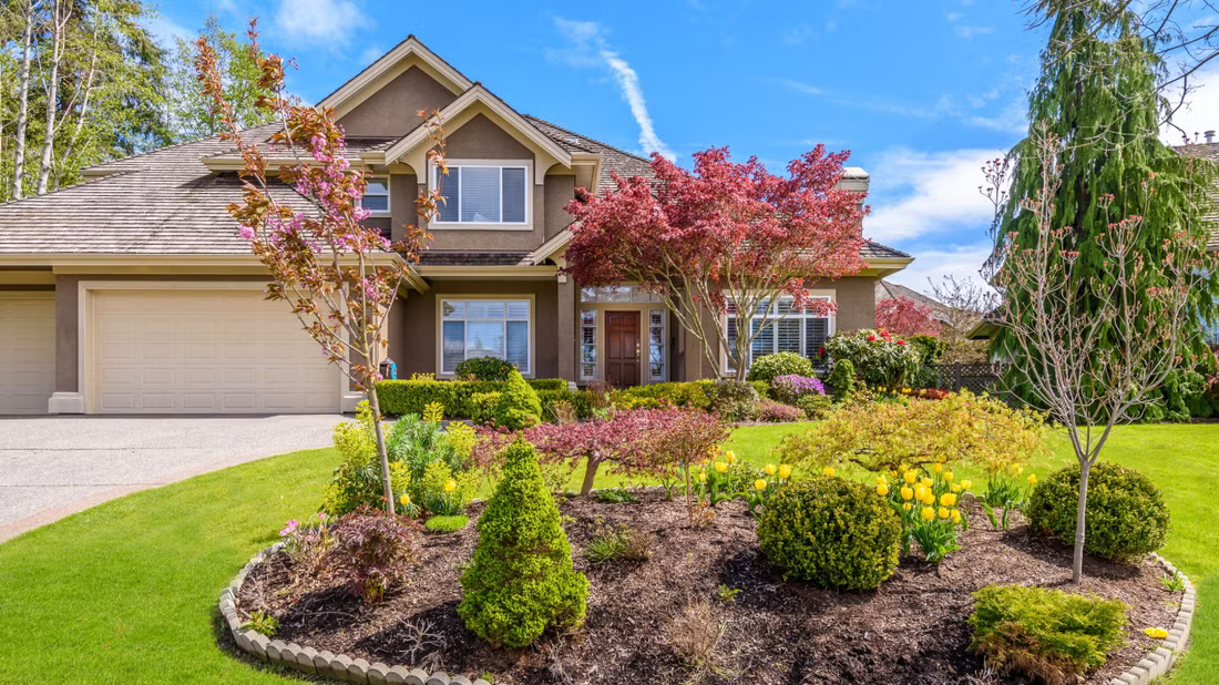 A large house with a lush green lawn and a garden in front of it.