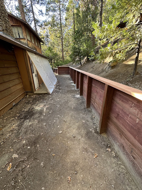 A wooden fence is surrounding a house in the woods.
