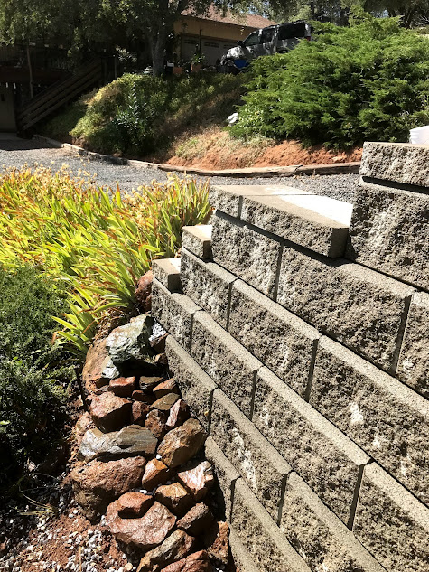 A brick wall surrounded by rocks and plants in a garden.