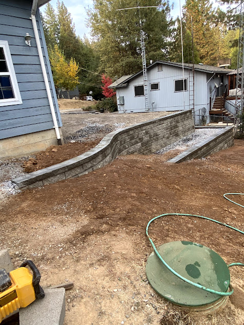 A hose is sitting in the dirt in front of a house.
