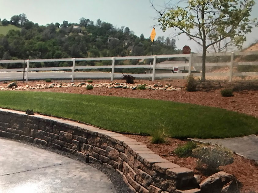 A white fence surrounds a lush green field