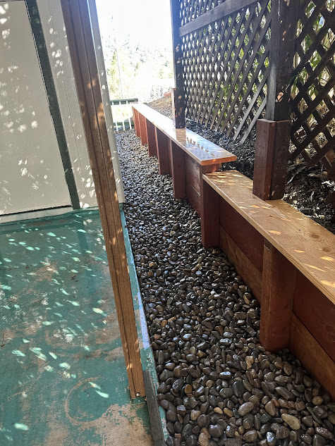 A wooden bench is sitting on top of a pile of rocks next to a fence.