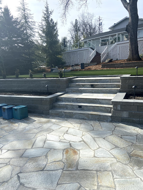 A stone patio with stairs leading up to a house.