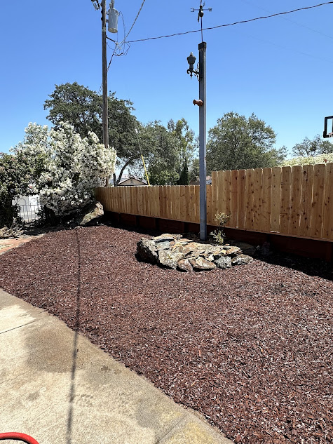 A wooden fence is surrounded by gravel and rocks