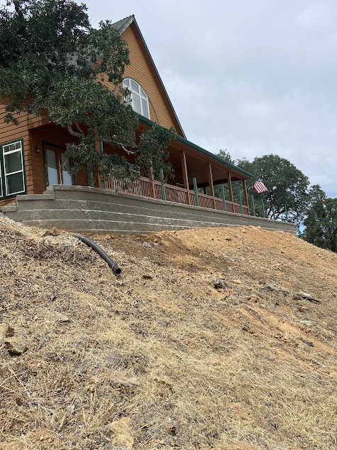 A large house is sitting on top of a dirt hill.