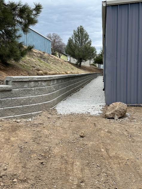 A concrete retaining wall is being built next to a shed.