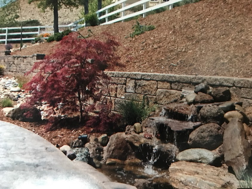 A waterfall is surrounded by rocks and a stone wall