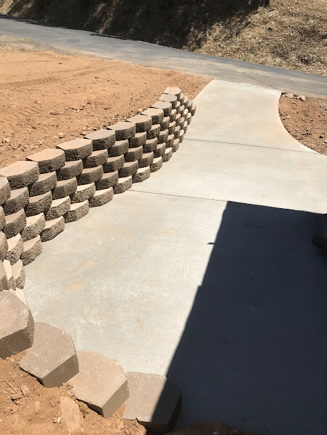 A concrete walkway with a stone wall along the side of it.