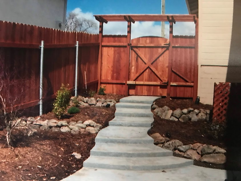A wooden fence with a concrete walkway leading to it
