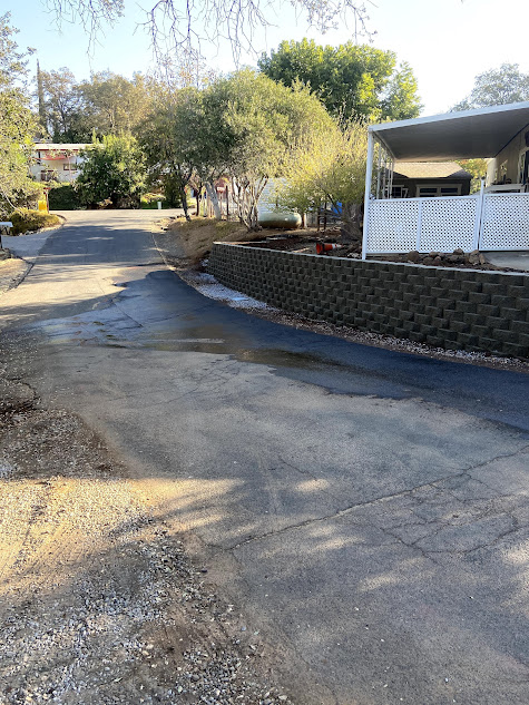 A mobile home is sitting on the side of a road next to a stone wall.