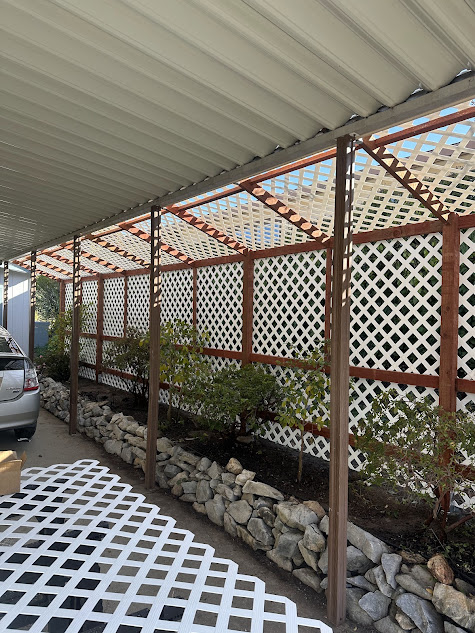 A car is parked under a covered patio next to a stone wall.